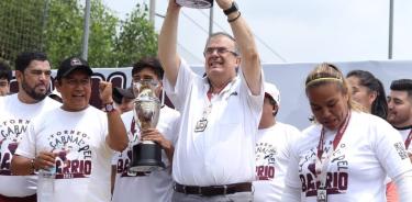 Marcelo Ebrard, aspirantes abswr el candidato presidencial de Morena, sostiene una copa de campeonato de futbol de los 