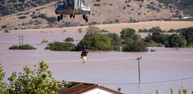 Un helicóptero y su tripulación trabajan para rescatar a personas varadas en una zona inundada