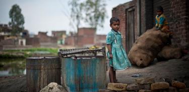 Una niña juega fuera de su vivienda en un cinturón de miseria de Uttar Pradesh, India