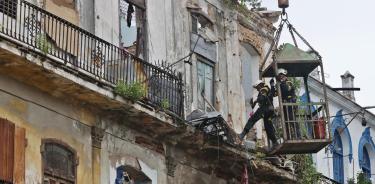 Bomberos acceden por un balcón del edificio colapsado en La Habana Vieja, en busca de personas atrapadas