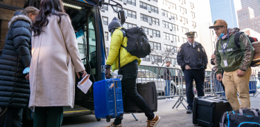 Inmigrantes venezolanos mientras suben a un transporte tras ser desalojados de un hotel, en Nueva York