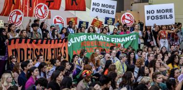 Activistas en la COP28 con pancartas exigiendo el abandono al uso de los combustibles fósiles