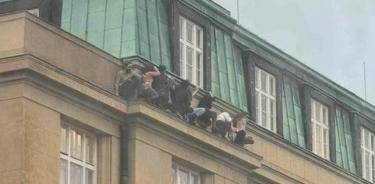 Estudiantes en una cornisa resguardándose de los disparos en la Universidad Carolina de Praga