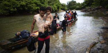 Un migrante venezolano carga a su hija Victoria de un año y medio luego de atravesar la selva del Darién
