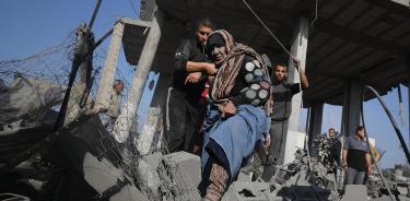 Una mujer es evacuada de su casa destruida por fuego israelí en Jan Yunis, sur de la Franja de Gaza