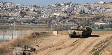Tanques israelíes patrullan la frontera, al fondo la destrucción de localidades de Gaza es total