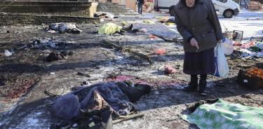 Una mujer camina por entre los cadáveres que dejó el impacto de un misil en un mercado de Donetsk, este de Ucrania