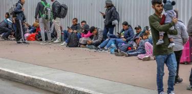 Migrantes esperan afuera de la garita internacional del Chaparral, en Tijuana