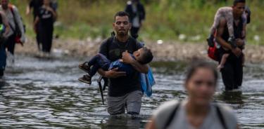 Migrantes cruzan un río por la peligrosa selva de Darién, entre Colombia y Panamá