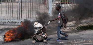 Un hombre empuja un carrito de bebé con comida en medio de los disturbios en Puerto Príncipe
