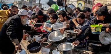 Palestinos se apelotonan junto a una de los escasos puntos de ayuda humanitaria en la Franja de Gaza