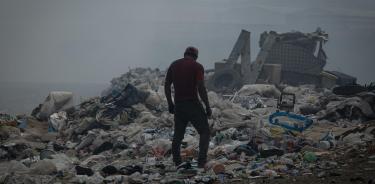 Un hombre camina entre basura este miércoles en un vertedero afectado por incendios forestales en el municipio de Villa Nueva