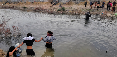 Inmigrantes se ayudan a cruzar el río Bravo, mientras los espera una patrulla fronteriza de EU