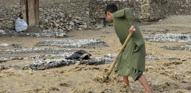 Una persona palea piedras en carreteras dañadas tras las inundaciones repentinas en el distrito de Ghorband de la provincia de Parwan, Afganistán