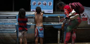 Una mujer y dos niños migrantes tras cruzar la selva del Darién en Lajas Blancas (Panamá).