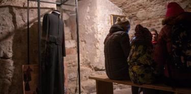 Varias personas descansan en la cripta de una iglesia convertida en museo, que se usó como refugio en los primeros días en la guerra de Ucrania.