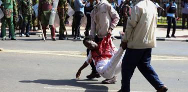 Dos hombres cargan el cuerpo de un joven muerto por disparos de la Policía en Nairobi