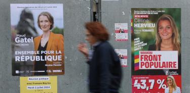 Una mujer pasa junto a un cartel de candidatos del Nouveau Front Populaire, en Francia