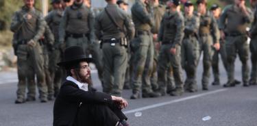 Joven ultraortodoxo hace una sentada en la vía pública enfrente de militares israelíes, en protesta por el reclutamiento obligatorio