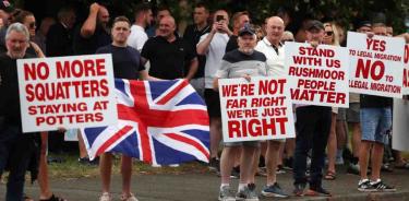 Manifestantes antiinmigrantes sostienen carteles durante una protesta frente al Hotel Potters International que alberga a inmigrantes en Aldershot, Gran Bretaña